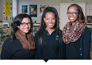 Three Henry Ford Academy students posing in a classroom in Detroit